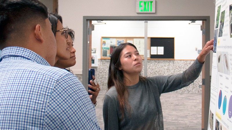 Kailee Tohonnie pointing at a poster.