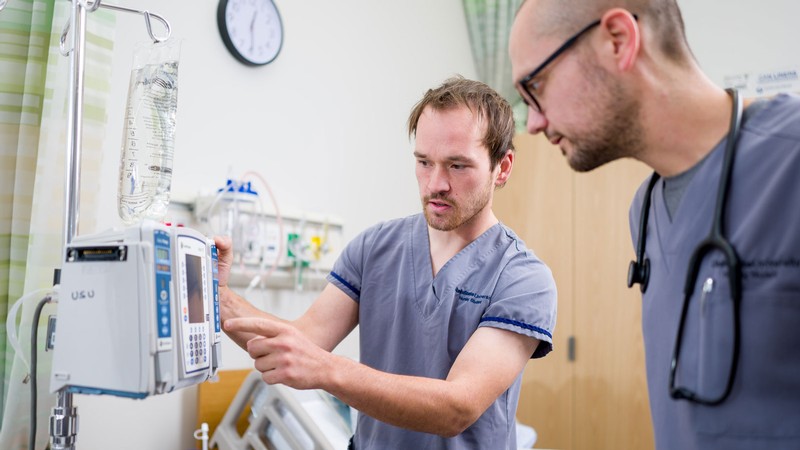 People looking at a device in a hospital room.