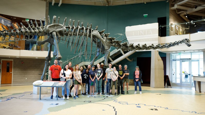 People standing in front of a museum dinosaur skeleton.