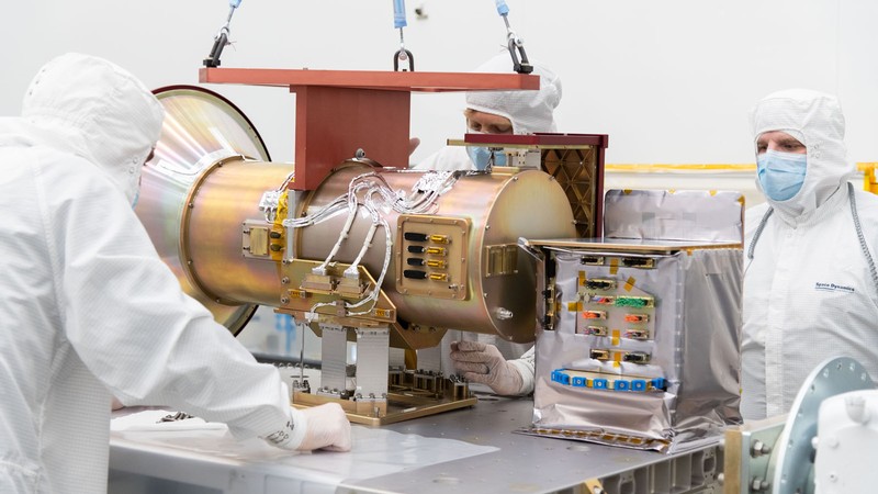 Scientists in protective equipment working on satellite equipment.