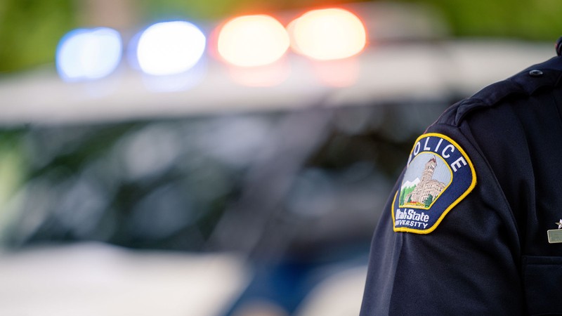 A police officer stands in front of a police car.