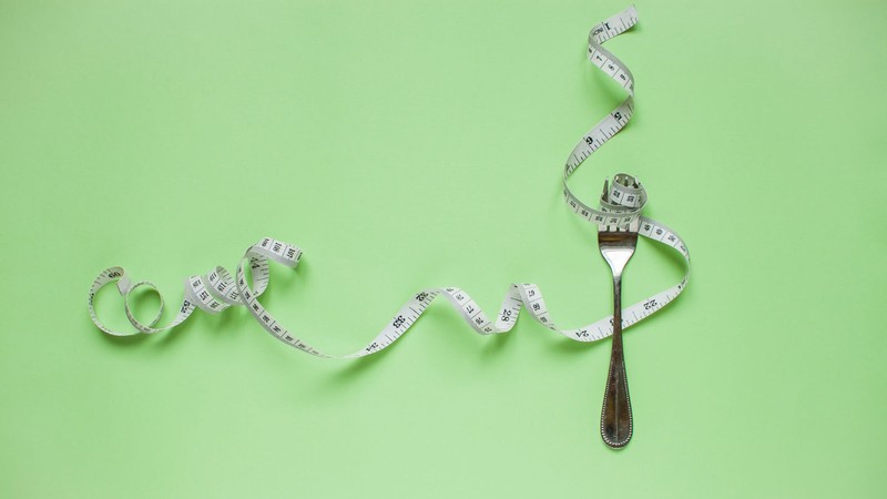 A photo illustration of a flexible measuring tape spiraling around a fork.