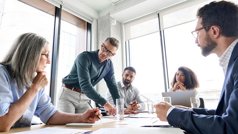 Employees sit around a table at a meeting.