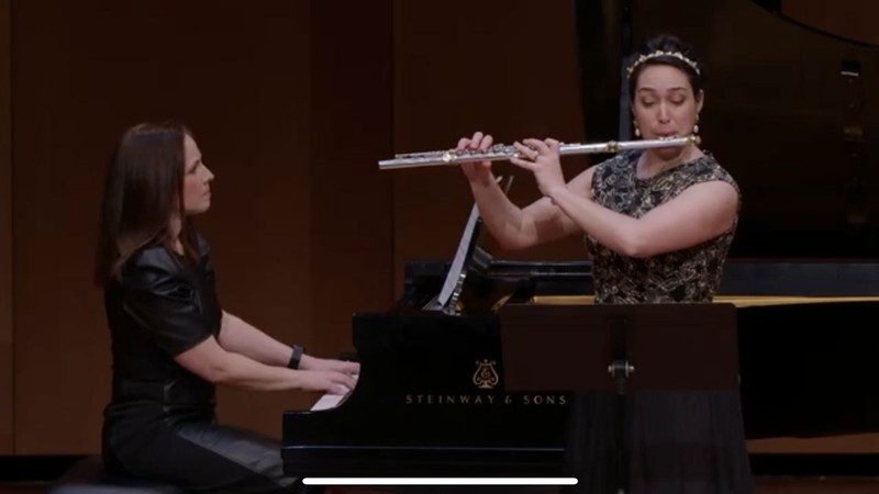 A person playing the piano and a person playing the flute.