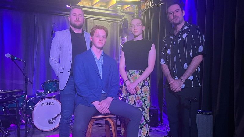 Musicians pose on stage for a photograph.