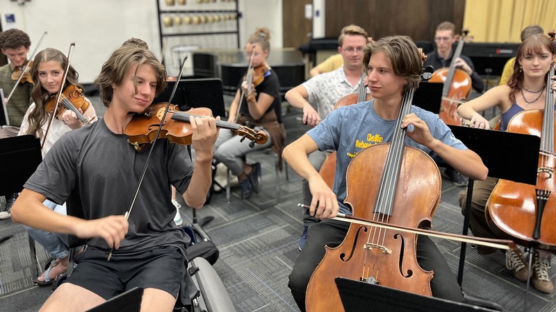 Jonathan Swank playing violin while identical twin Joshua Swank plays cello.