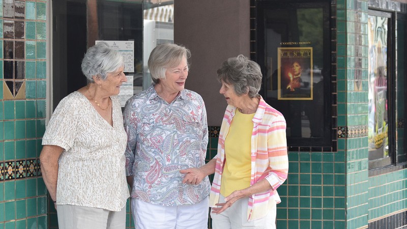 Women speaking by a movie theater box office.