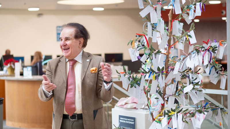 Mehdi Heravi standing next to a small tree with written notes tied to it.