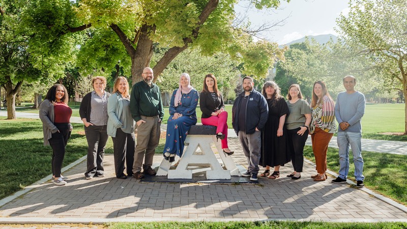 People posing for a group photo around USU's Block A.