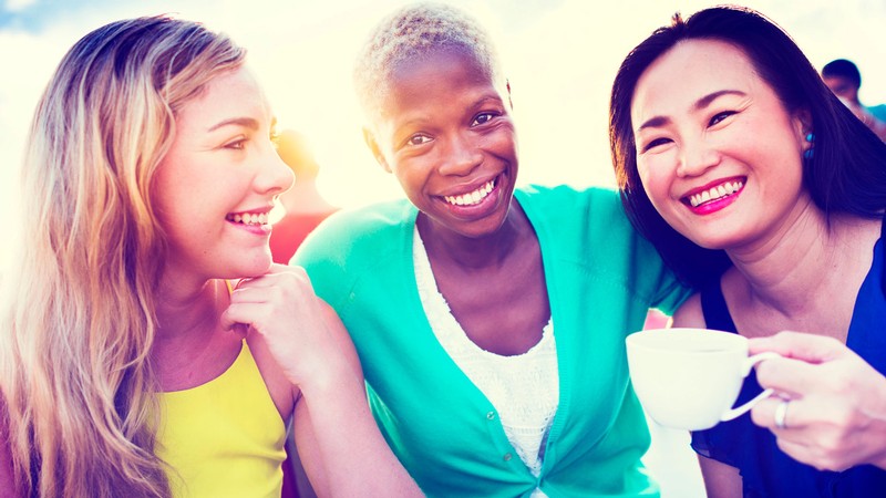 Three women smiling and embracing.