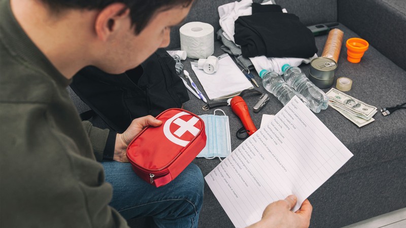 A person looking at an emergency kit and checklist.