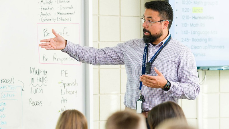A teacher at the front of a classroom.