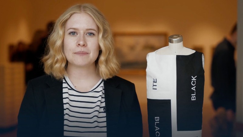 A student standing next to a clothing design.
