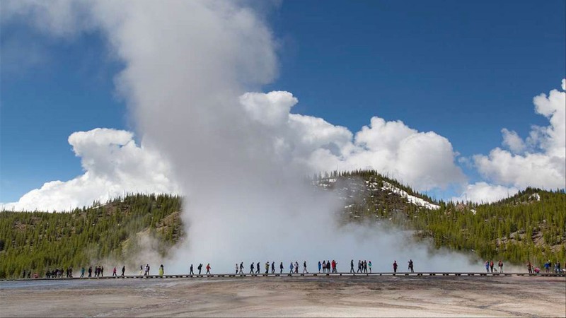Tourists walking past a hot pot in Yellowstone.