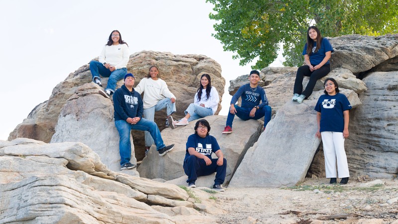 Native American students posing for a photo on a rock formation.
