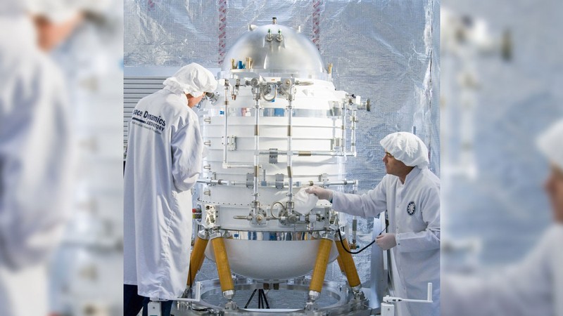 Engineers working on a large scientific instrument in a cleanroom.