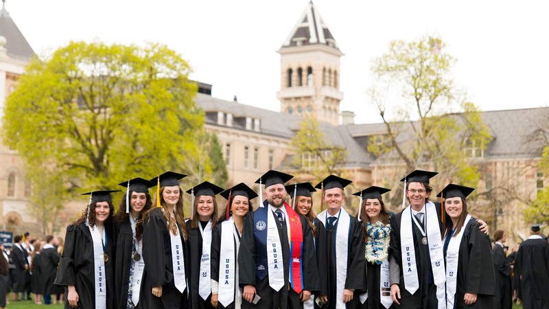 People in graduation clothing posing in front of Old Main.