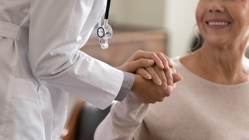 A woman holds hands with a doctor in a clinic.