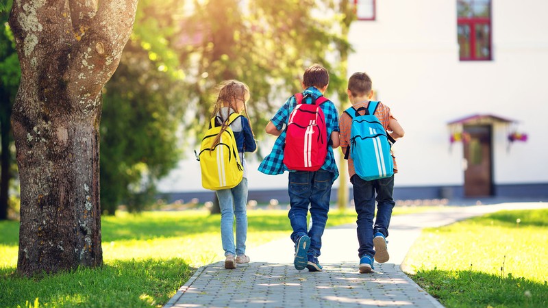 Three children walking on a sidewalk.