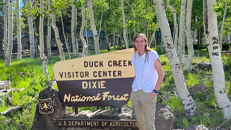 Callie Davis posing by a sign that says Duck Creek Visitor Center, Dixie National Forest.