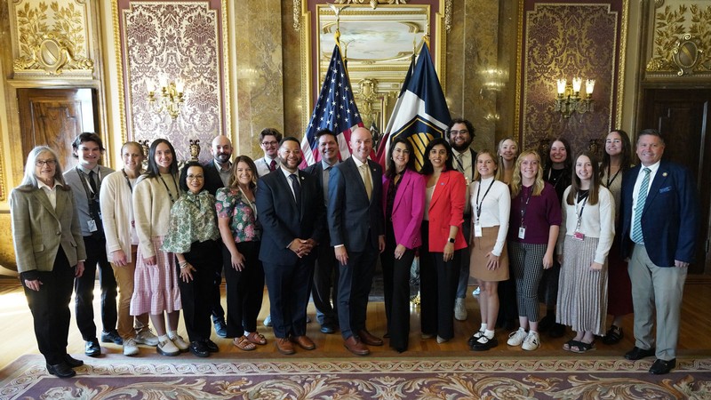People standing with Spencer Cox for a group photo.
