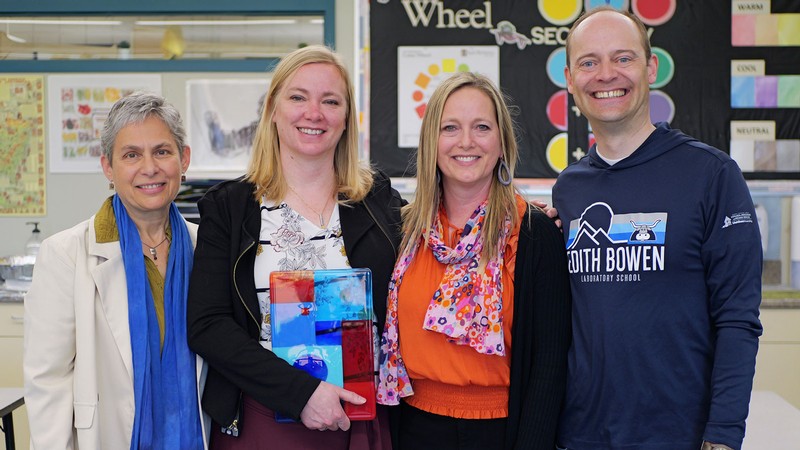 Educators posing with an award in a classroom.
