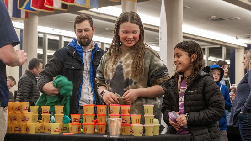 People looking at stacks of Play-Doh on a table.