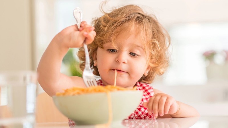 A toddler eating spaghetti.
