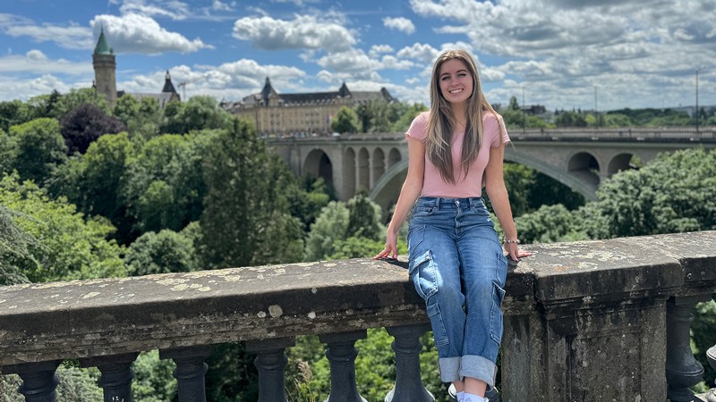 A woman sits on a bridge overlooking a college campus in Spain.