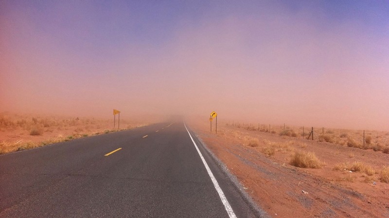 Dust blowing over a desert highway.