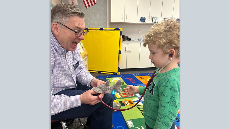 Kerry Rood examining a stuffed animal with a preschooler in a classroom.
