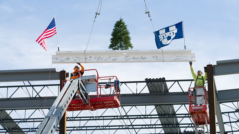 Workers raise a steel beam into place during a building constuction