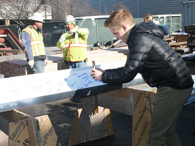 USU student Jesse Steadman signs building beam.