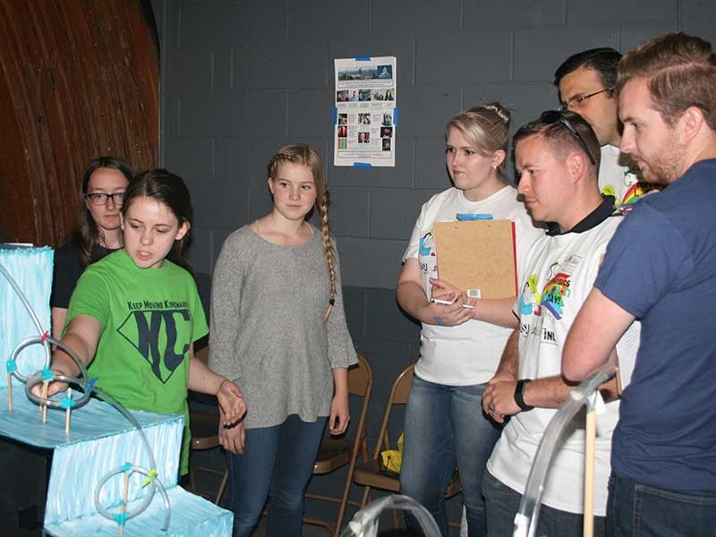 Teens with amusement park ride model.