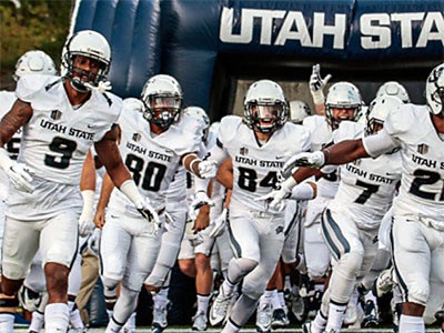 Utah State University football players running onto the field