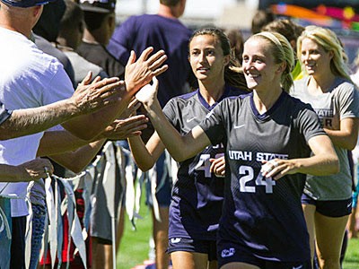 USU women's soccer players celebrating on the sidelines with fans