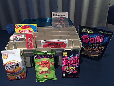 a fishing tackle box with snacks inside and a book