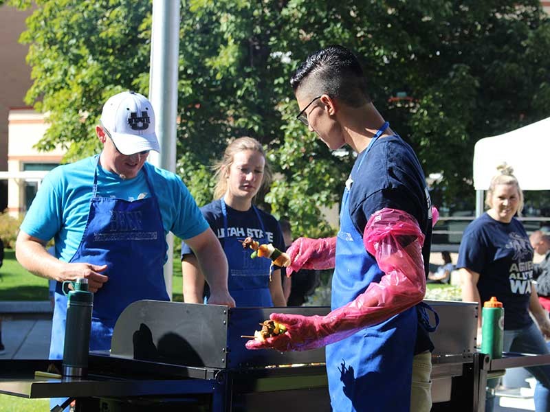 USU students serving food from a grill.