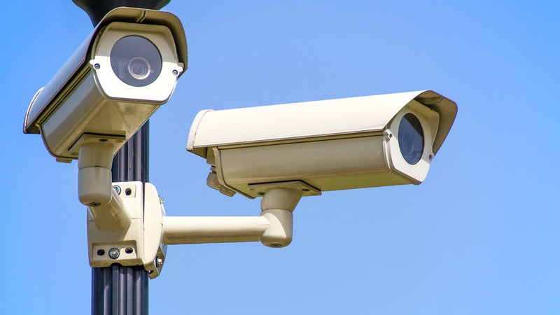 Security cameras are seen attached to a lamppost.