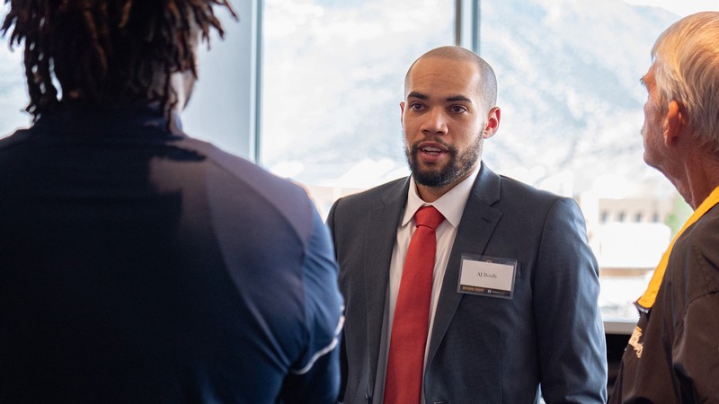 A man in a suit speaks in a crowd.