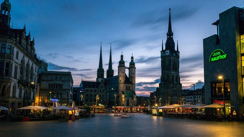Historic and modern buildings line a canal in Halle, Germany.