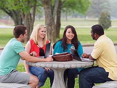 a group of diverse young people at a table outdoors