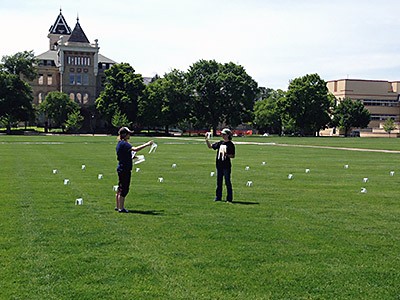 two Extension workers and water catch cups on USU's Quad