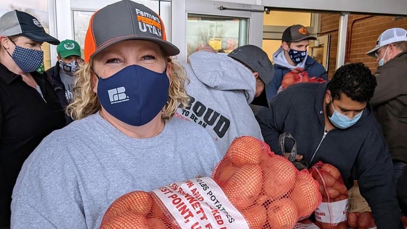 Farmers Feeding Utah volunteer hands out bags of potatoes.