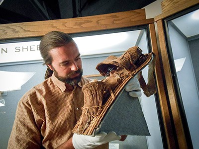 Archaeologist Tim Riley holding a one-of-a-kind Fremont figurine-cradleboard.