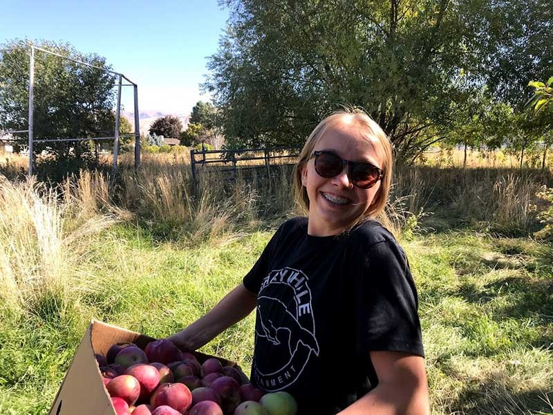 volunteer with a bushel of apples