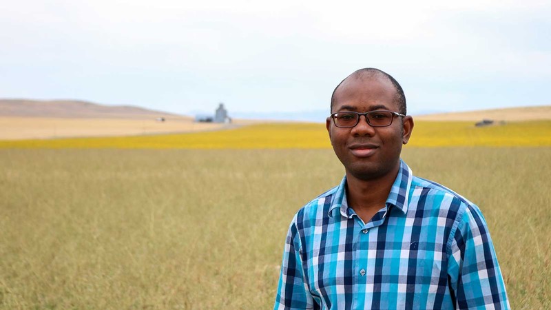 Idowu Atoloye poses for a photo in a field.