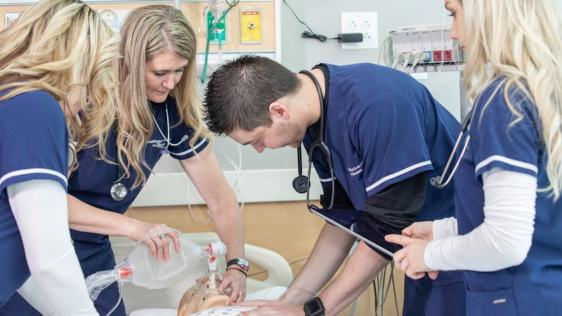 nursing students practice on a dummy.