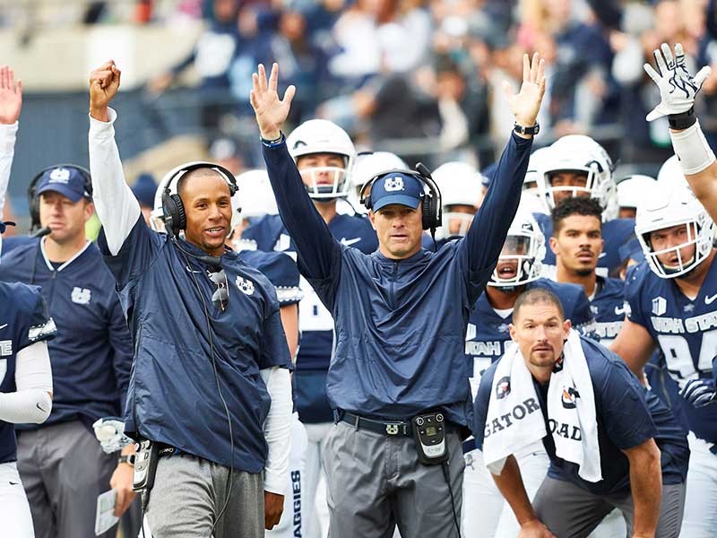 USU Football Coach Matt Wells (center, U State hat)