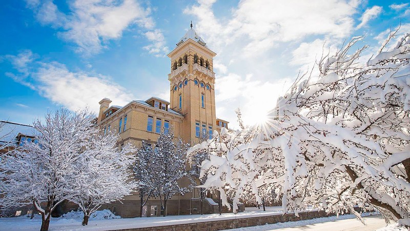 Old Main is seen through snow-covered trees.